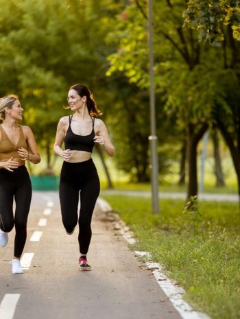 dwie kobiety biegające po drodze w parku